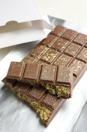 Photo of Delicious Dubai chocolate with pistachios and knafeh on table, closeup