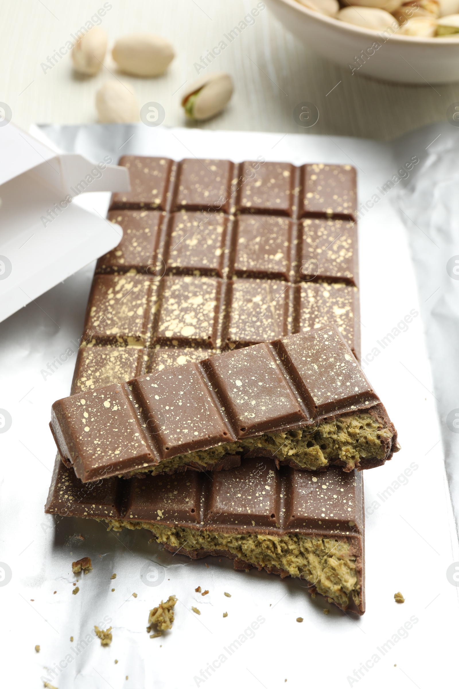 Photo of Delicious Dubai chocolate with pistachios and knafeh on table, closeup