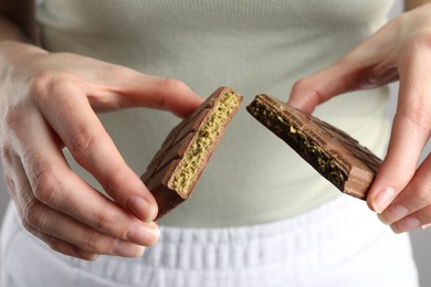 Photo of Woman holding pieces of delicious Dubai chocolate with pistachios and knafeh, closeup