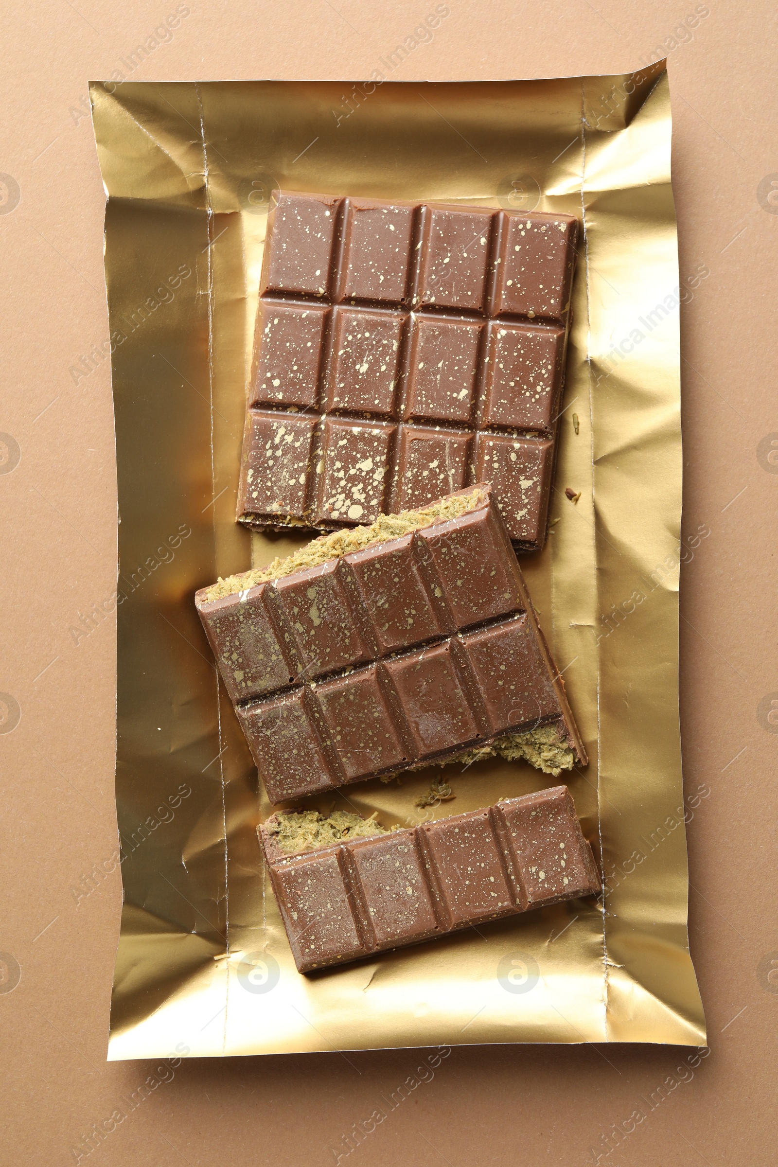 Photo of Pieces of delicious Dubai chocolate with pistachios and knafeh on dark beige background, top view