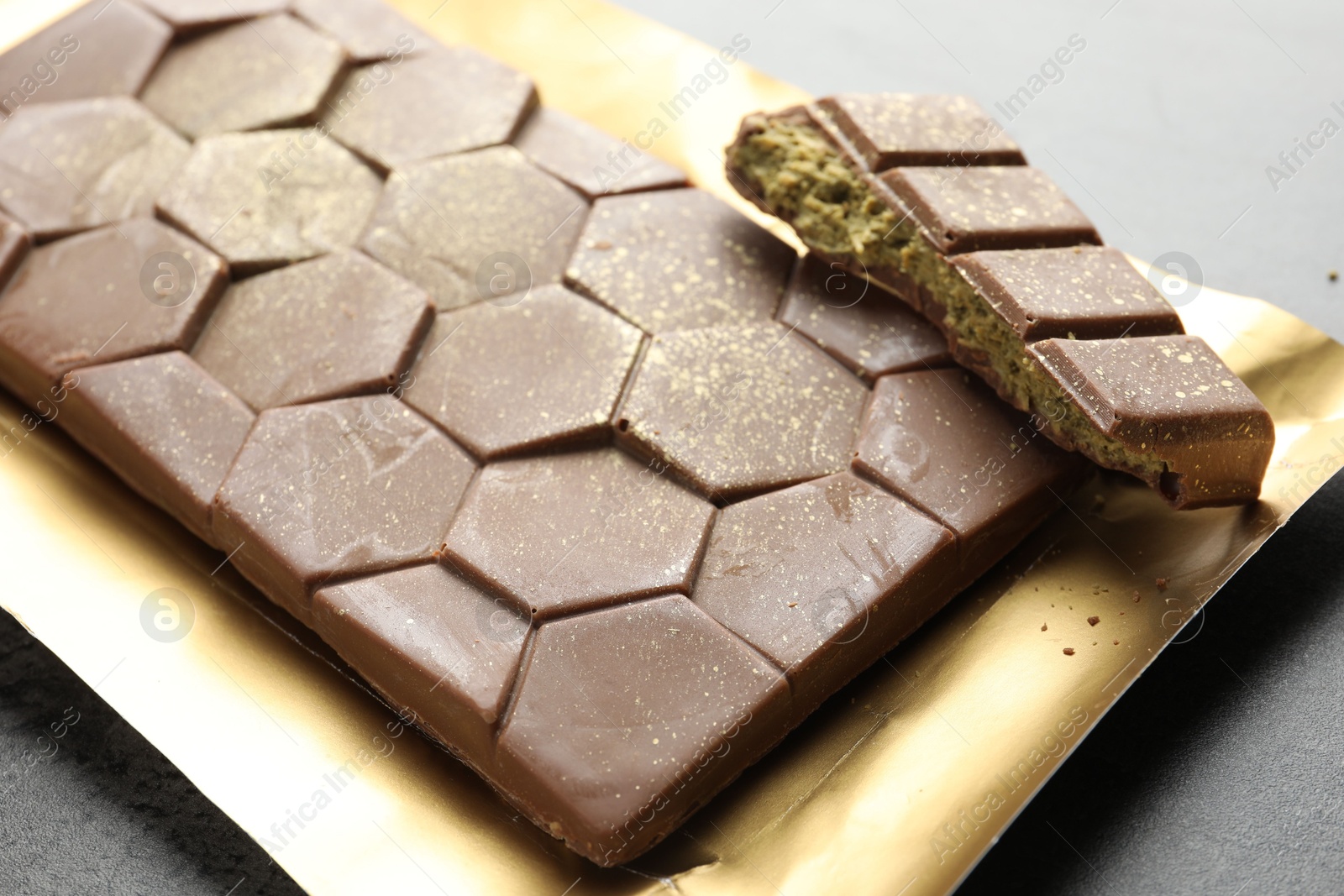 Photo of Delicious Dubai chocolate with pistachios and knafeh on grey table, closeup