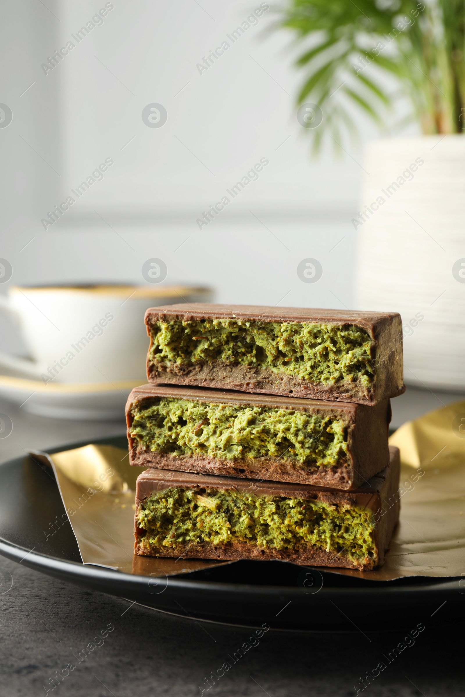 Photo of Pieces of delicious Dubai chocolate with pistachios and knafeh on grey table, closeup