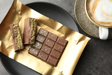 Pieces of delicious Dubai chocolate with pistachios, knafeh and coffee on grey table, flat lay