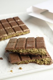 Pieces of delicious Dubai chocolate with pistachios and knafeh on white table, closeup