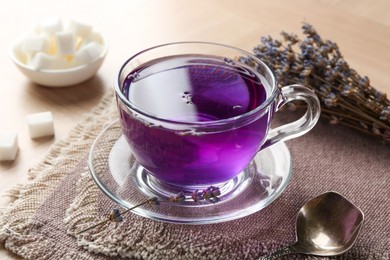 Photo of Aromatic lavender tea in glass cup and spoon on table, closeup