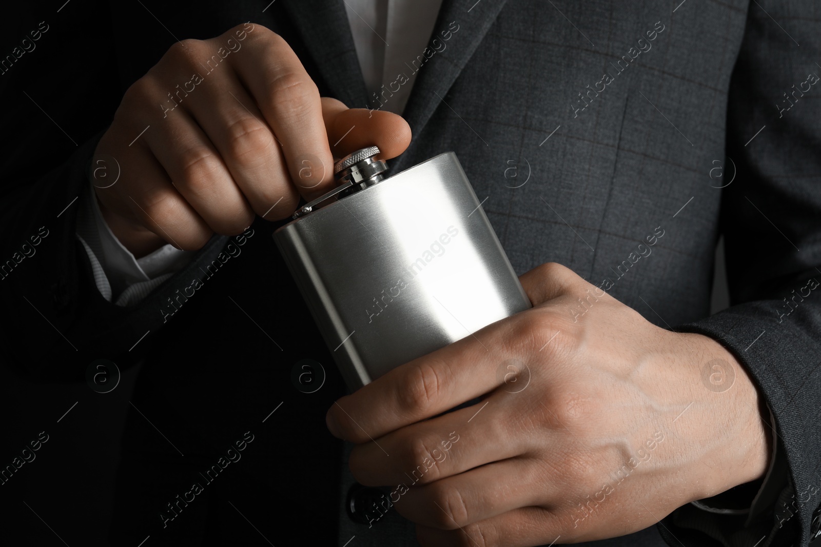 Photo of Man in suit holding metal hip flask, closeup view