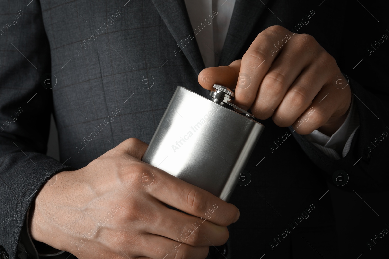 Photo of Man in suit holding metal hip flask, closeup view