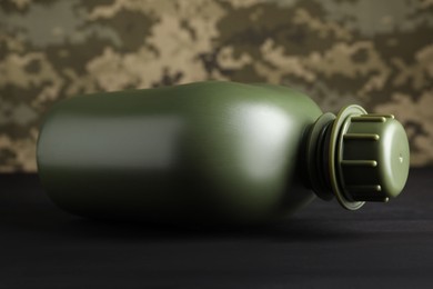 Photo of Green plastic canteen on black wooden table, closeup