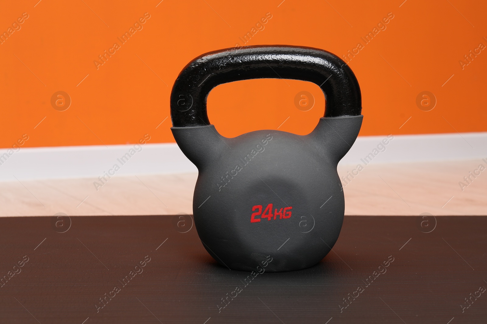 Photo of One kettlebell on mat indoors, closeup. Sport equipment