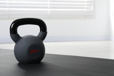 Photo of One kettlebell and mat on floor indoors, closeup. Space for text