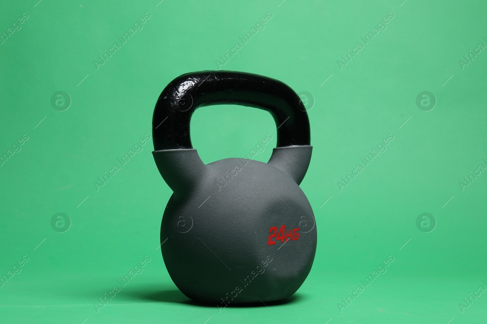 Photo of One heavy kettlebell on green background, closeup