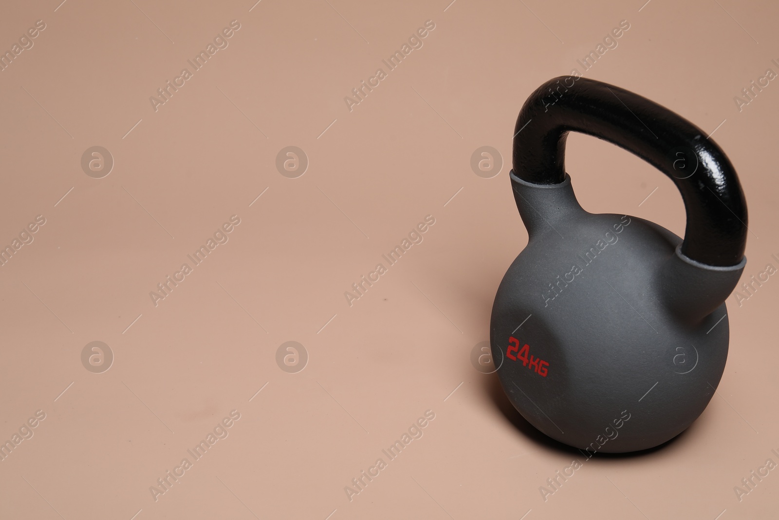 Photo of One heavy kettlebell on beige background. Space for text