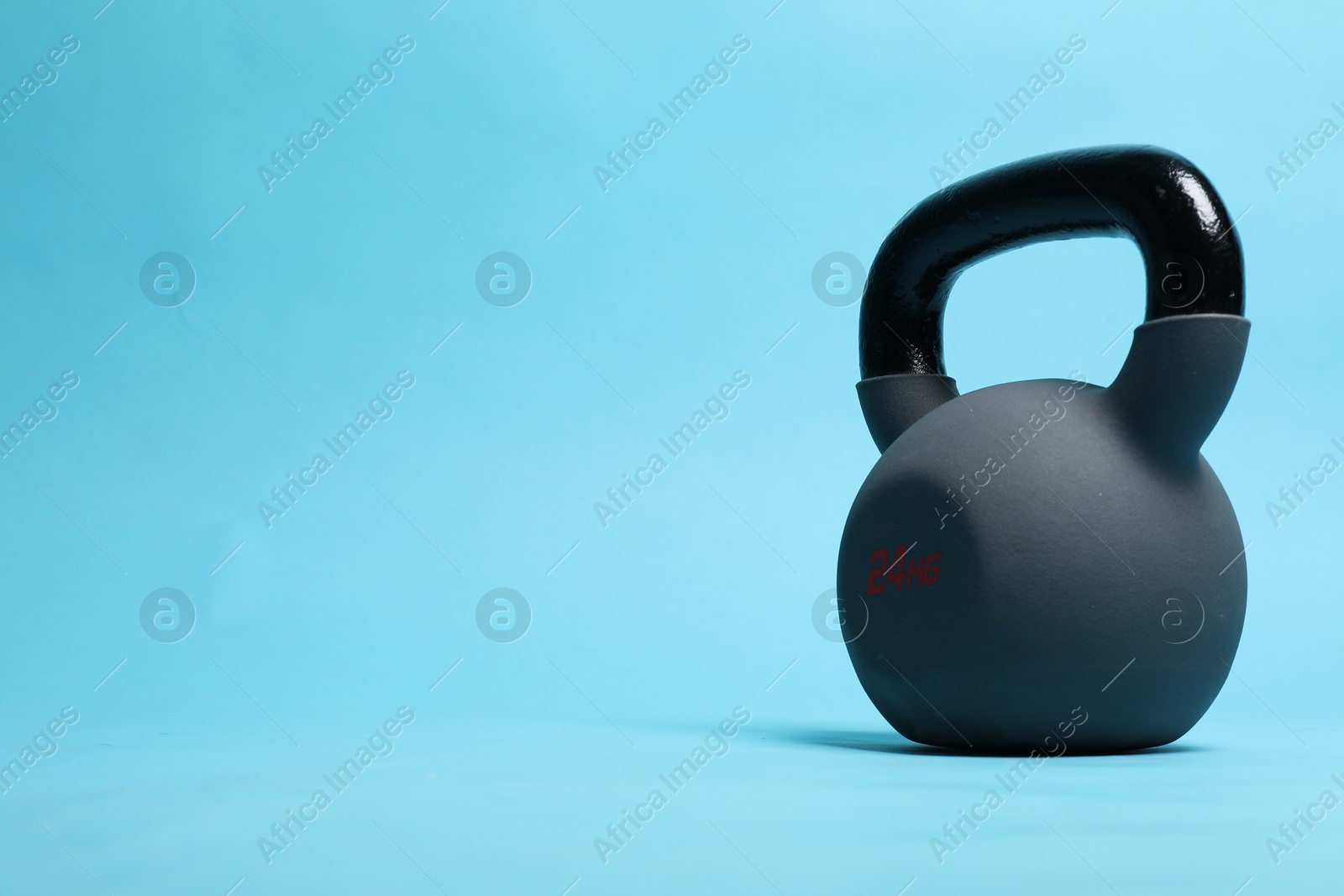 Photo of One heavy kettlebell on light blue background. Space for text