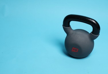 Photo of One heavy kettlebell on light blue background. Space for text