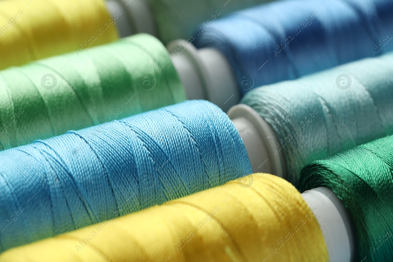 Photo of Different spools of sewing threads as background, closeup