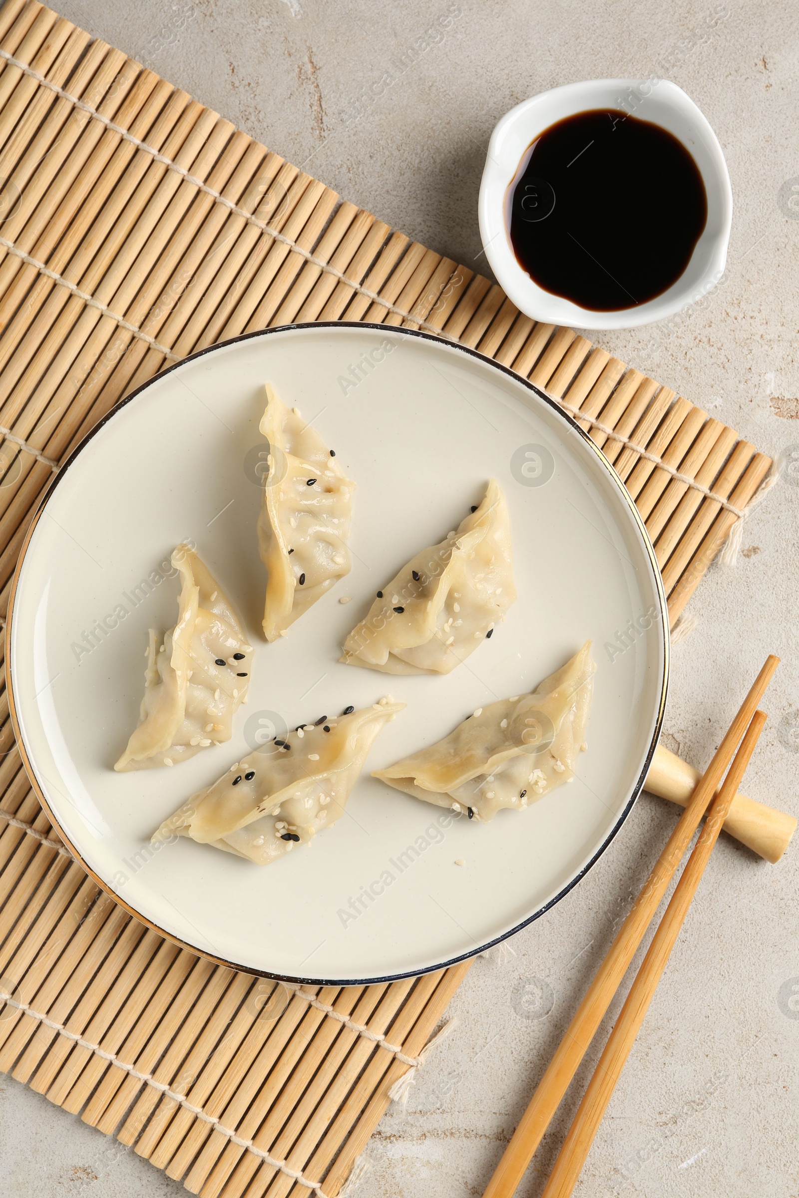 Photo of Delicious gyoza dumplings with sesame seeds served on light table, top view