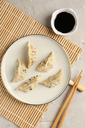 Photo of Delicious gyoza dumplings with sesame seeds served on light table, top view