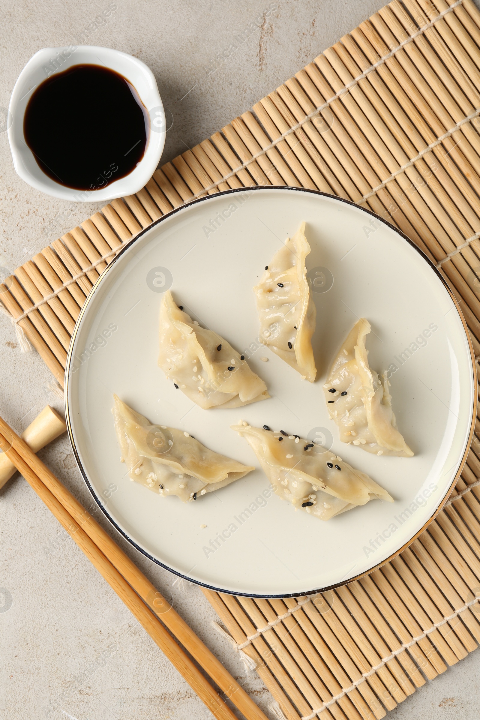 Photo of Delicious gyoza dumplings with sesame seeds served on light table, top view