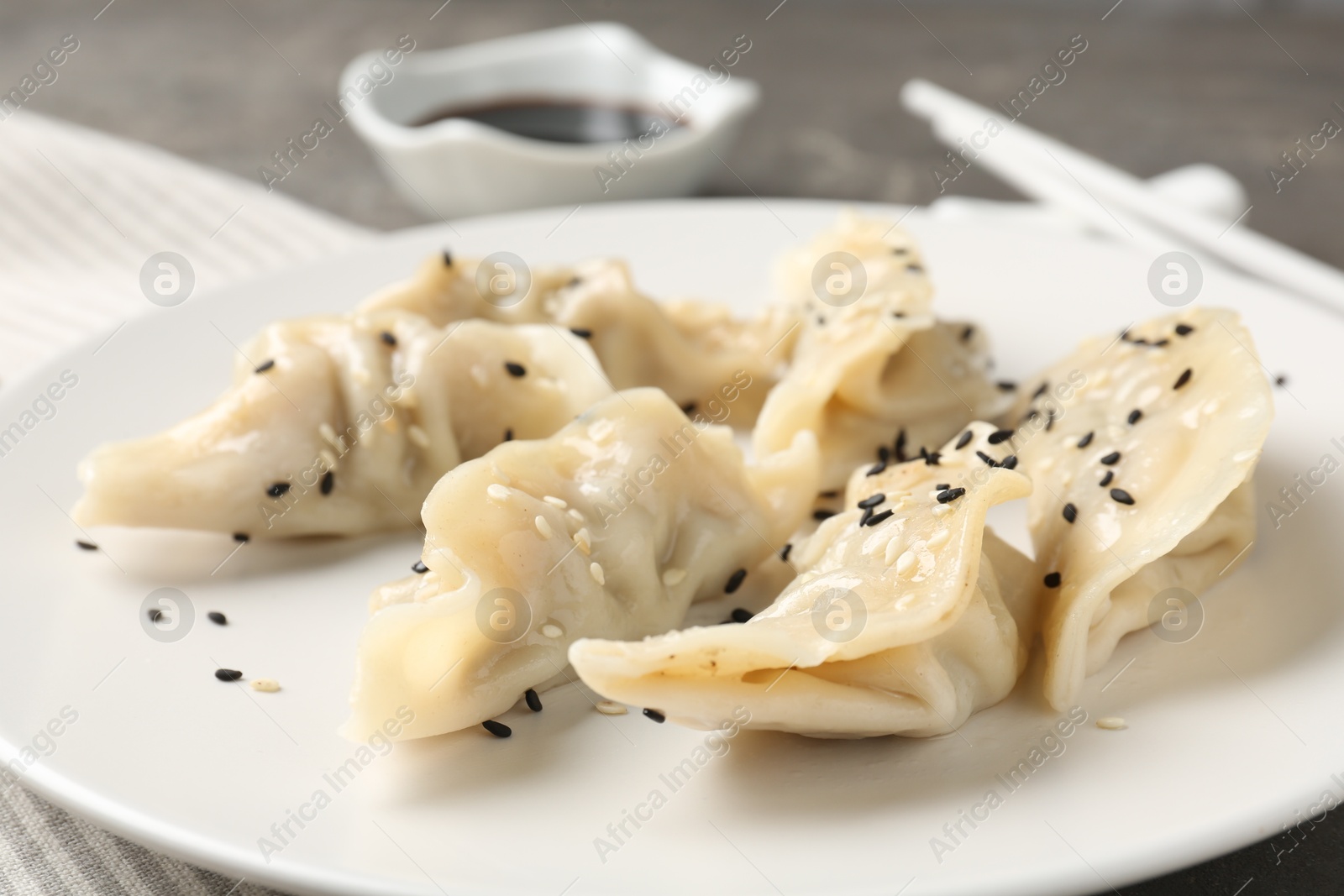 Photo of Delicious gyoza dumplings with sesame seeds served on table, closeup