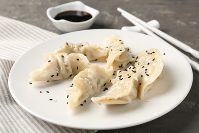 Photo of Delicious gyoza dumplings with sesame seeds served on grey table, closeup