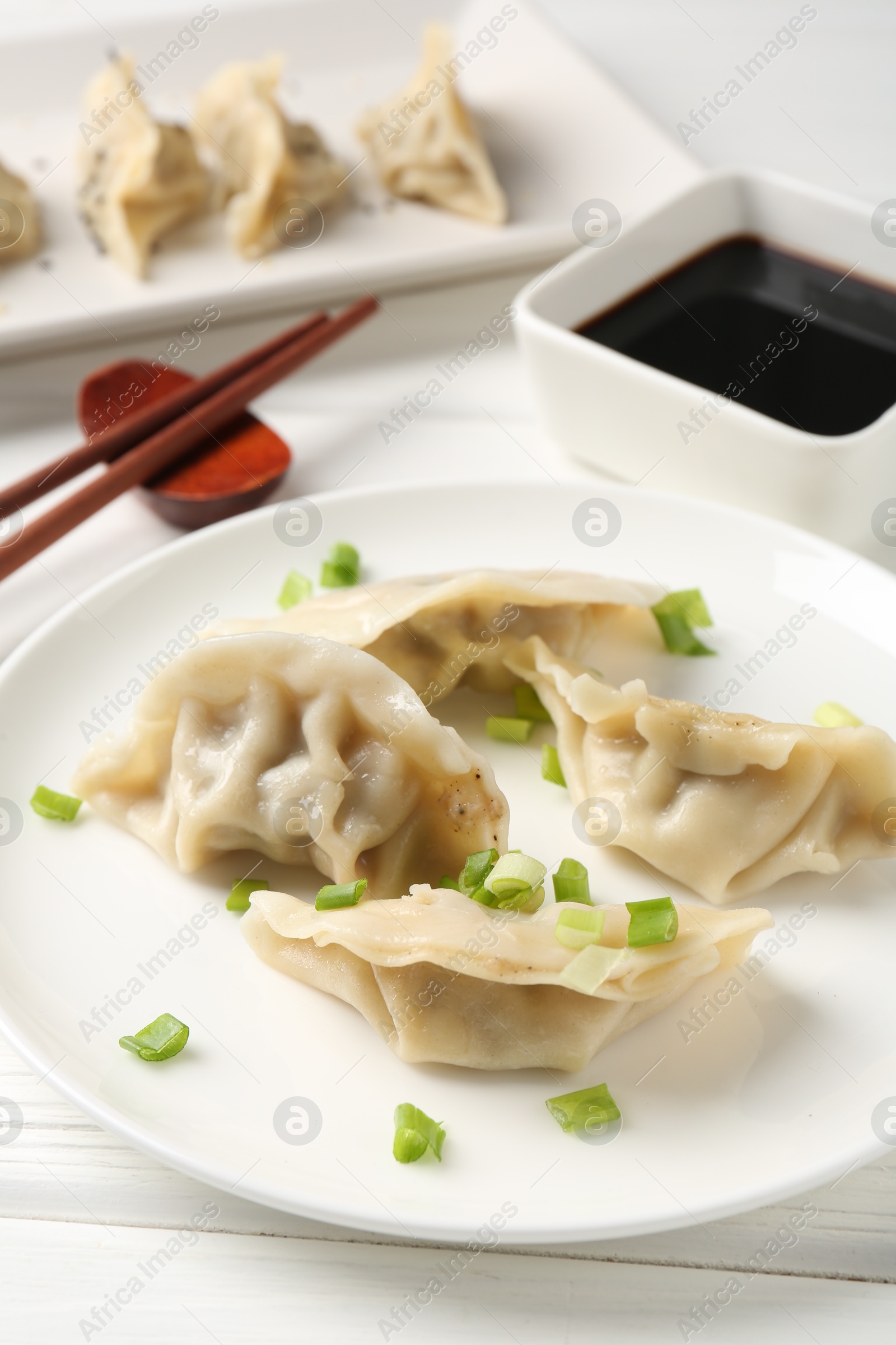 Photo of Delicious gyoza dumplings with chives served on white table, closeup