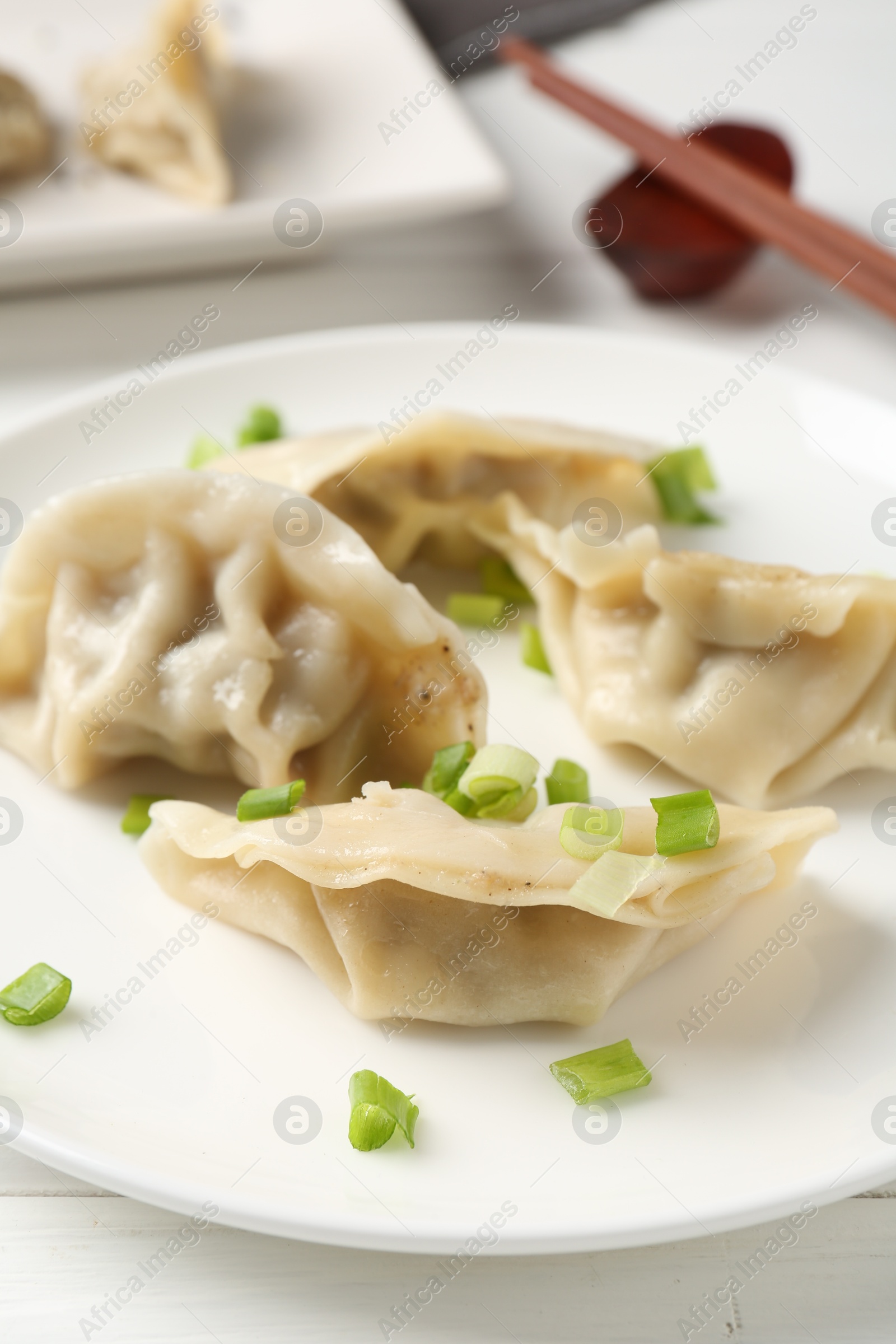 Photo of Delicious gyoza dumplings with chives served on white table, closeup