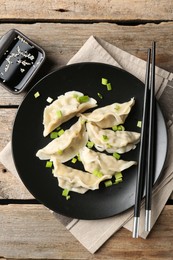 Photo of Delicious gyoza dumplings with chives served on wooden table, top view