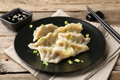 Photo of Delicious gyoza dumplings with chives served on wooden table, closeup