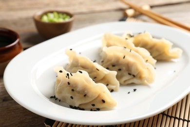 Photo of Delicious gyoza dumplings with sesame seeds served on table, closeup