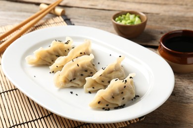 Photo of Delicious gyoza dumplings with sesame seeds served on wooden table, closeup