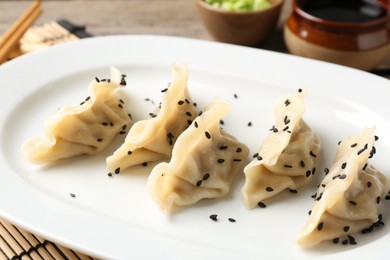 Photo of Delicious gyoza dumplings with sesame seeds served on table, closeup