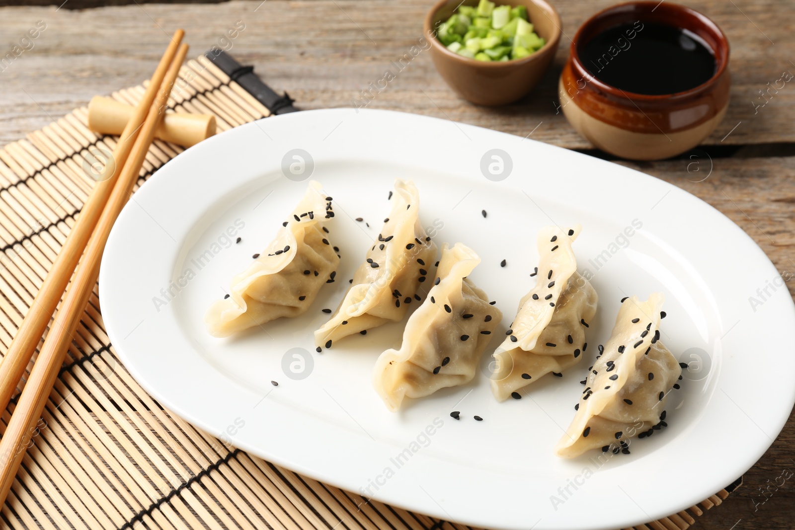 Photo of Delicious gyoza dumplings with sesame seeds served on wooden table, closeup