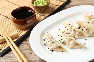 Photo of Delicious gyoza dumplings with sesame seeds served on wooden table, closeup