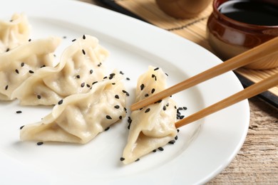 Photo of Eating tasty gyoza dumplings at wooden table, closeup