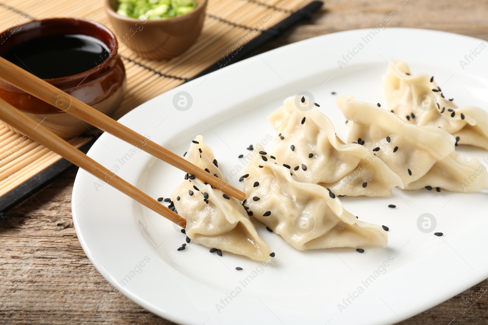 Photo of Eating tasty gyoza dumplings at wooden table, closeup