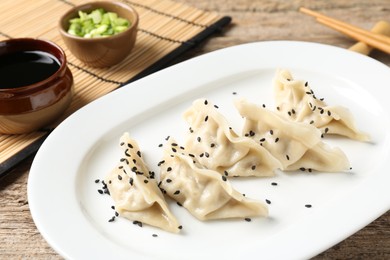 Photo of Delicious gyoza dumplings with sesame seeds served on wooden table, closeup