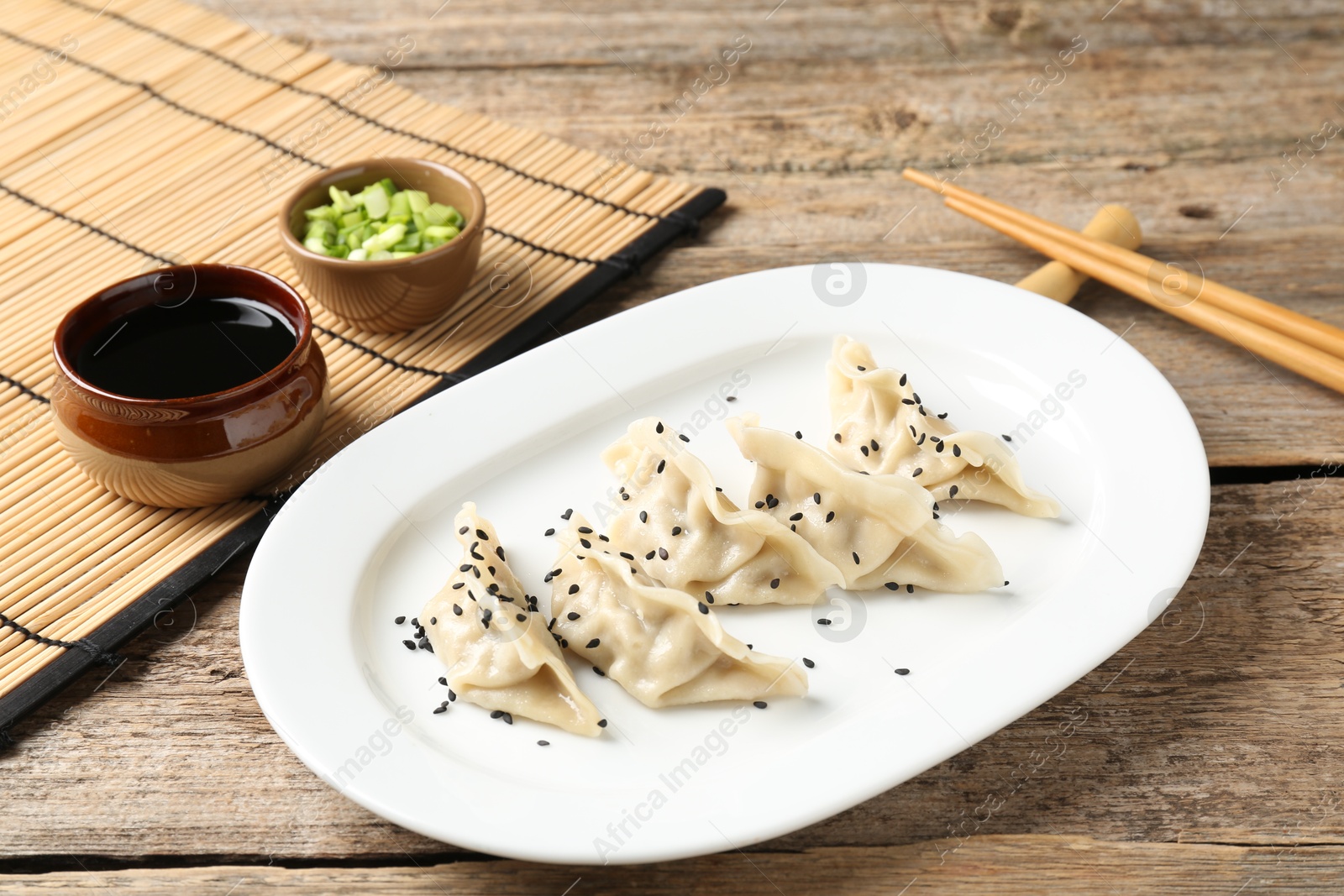 Photo of Delicious gyoza dumplings with sesame seeds served on wooden table