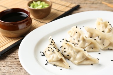 Photo of Delicious gyoza dumplings with sesame seeds served on wooden table, closeup