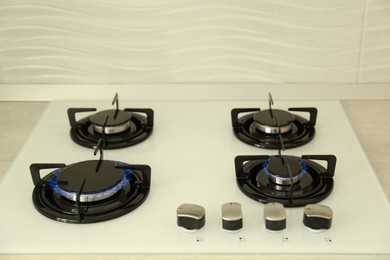 Photo of Modern stove with burning blue flames in kitchen