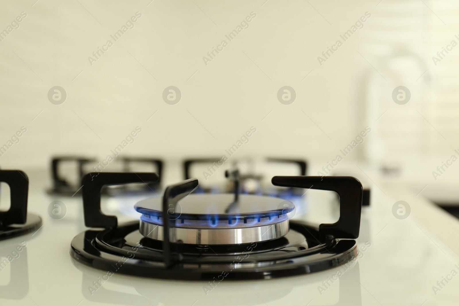 Photo of Gas burner of modern stove with burning blue flame, closeup