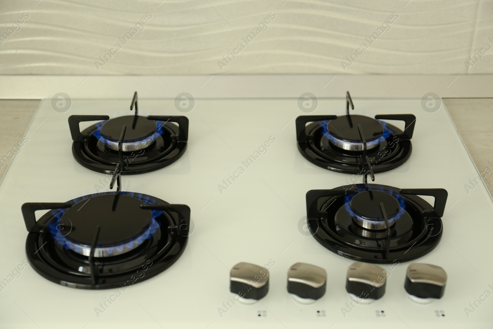 Photo of Modern stove with burning blue flames in kitchen