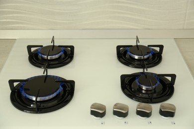 Photo of Modern stove with burning blue flames in kitchen