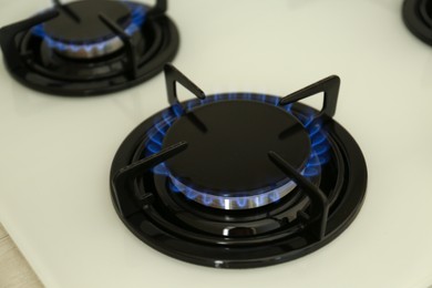 Photo of Gas burner of modern stove with burning blue flame, closeup