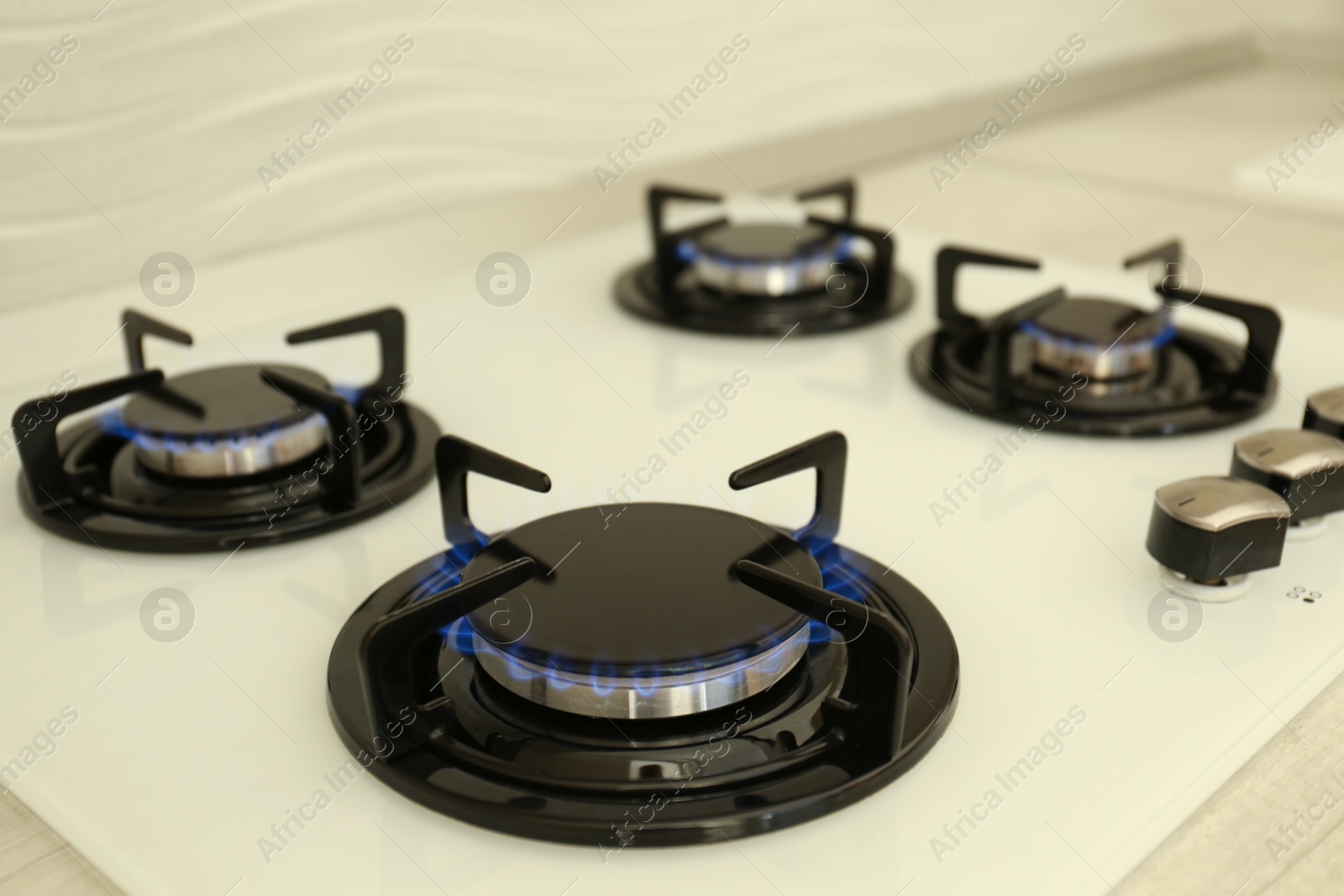 Photo of Modern stove with burning blue flames in kitchen