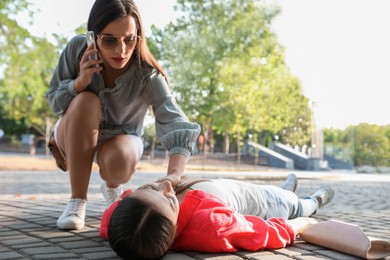 Photo of Woman calling ambulance to help unconscious person with heart attack in park