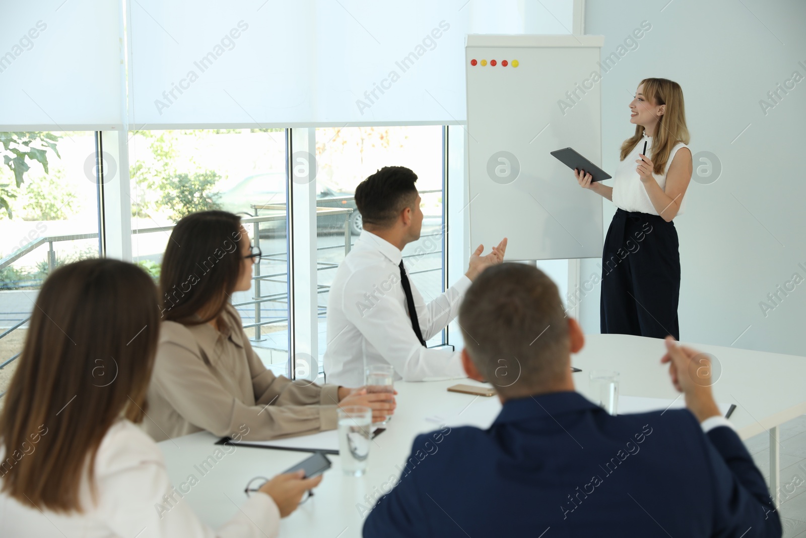 Photo of Female business coach talking to audience in office