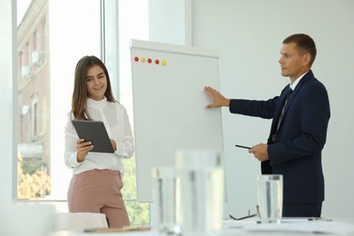 Office employees talking near whiteboard at workplace