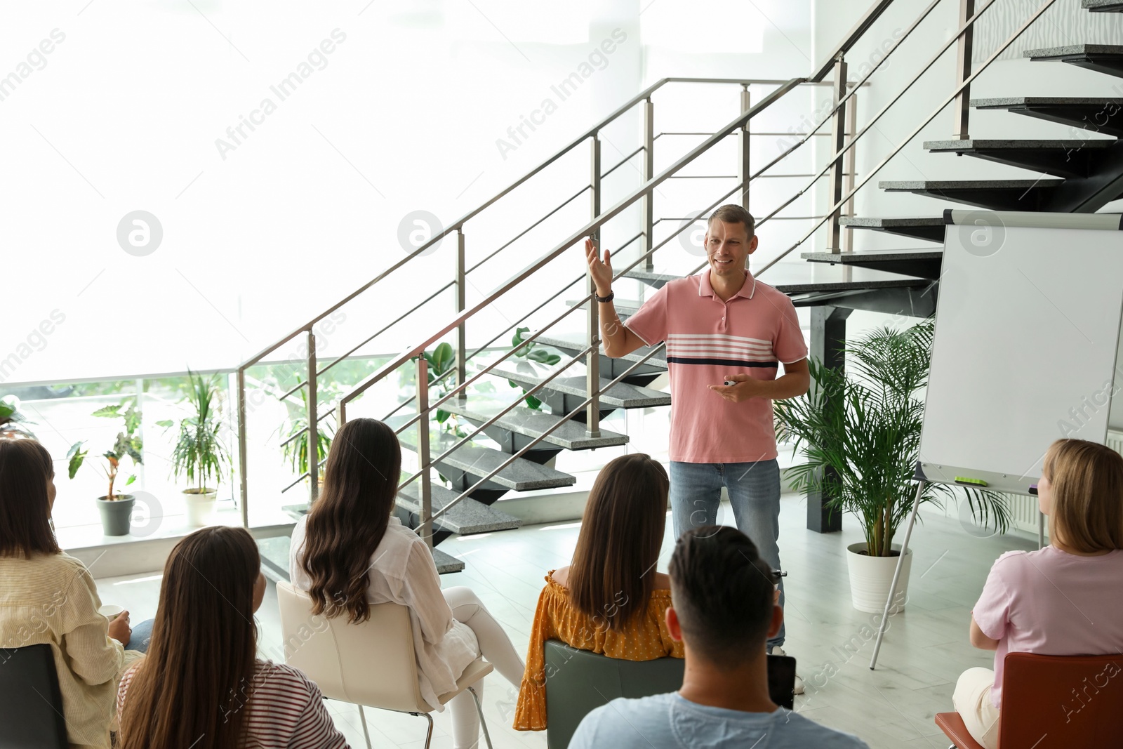 Photo of Male lecturer in casual clothes talking to audience indoors