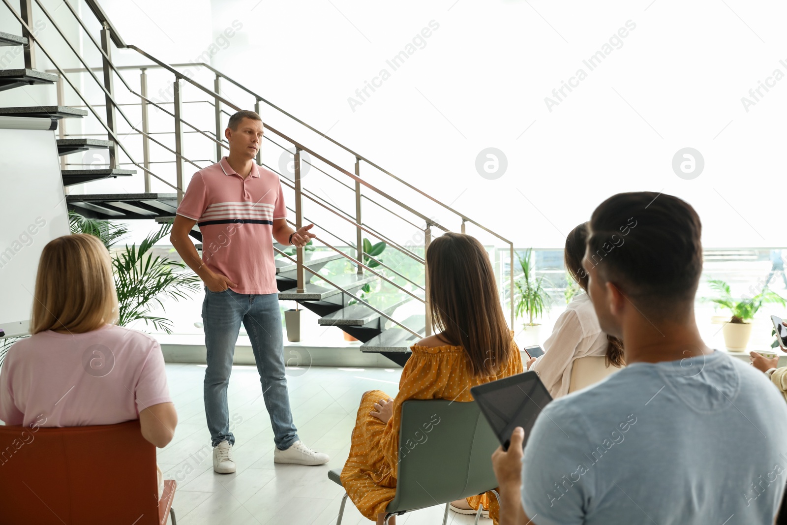 Photo of Male lecturer in casual clothes talking to audience indoors