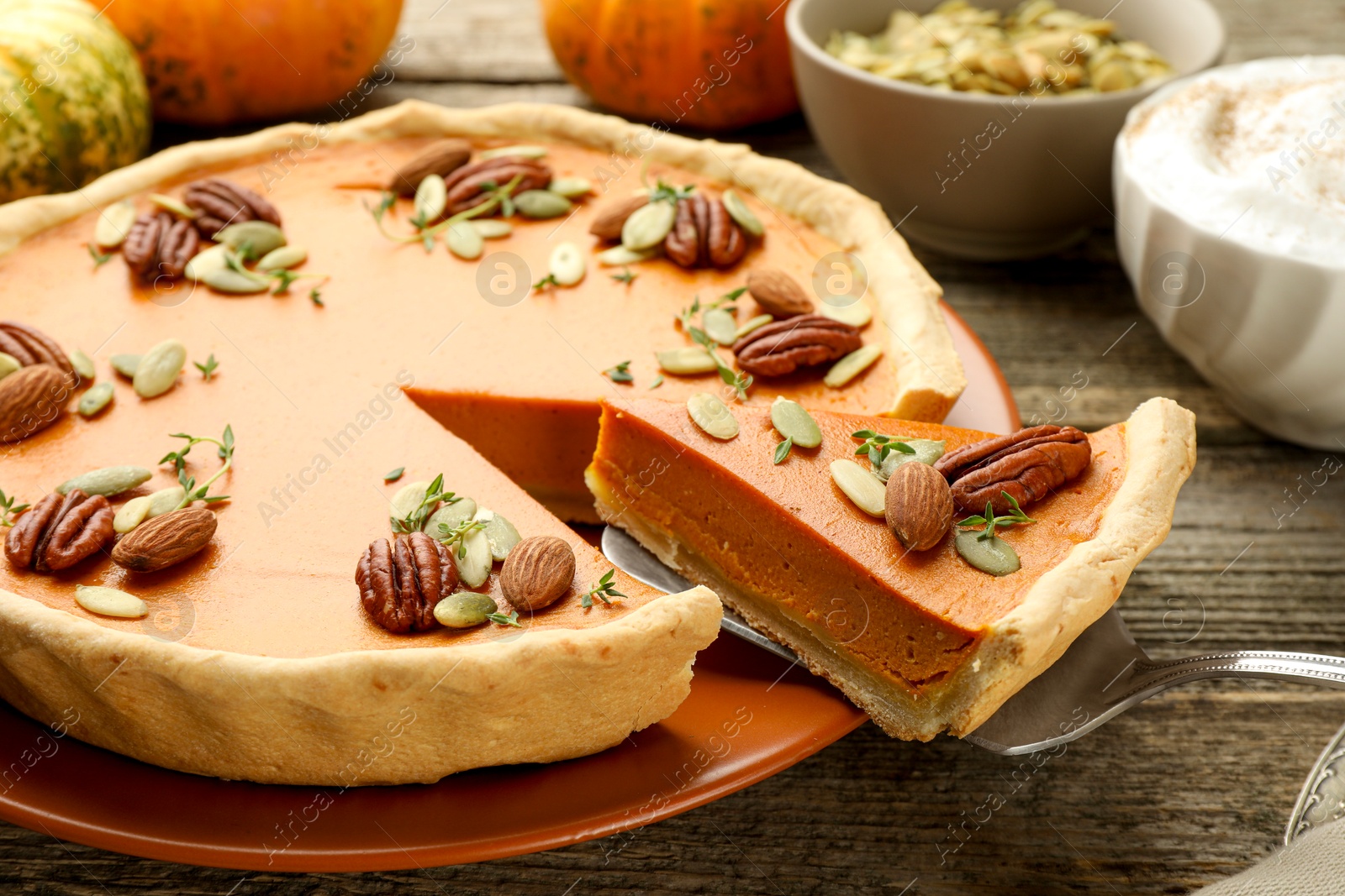 Photo of Taking piece of tasty homemade pumpkin pie at wooden table, closeup